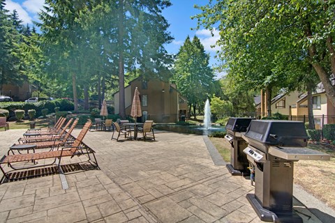 A patio with chairs and a fountain in the background.