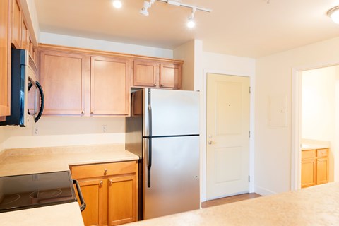 A kitchen with wooden cabinets and a stainless steel refrigerator.