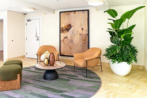 A living room with a chair, ottoman, and a large painting on the wall.
