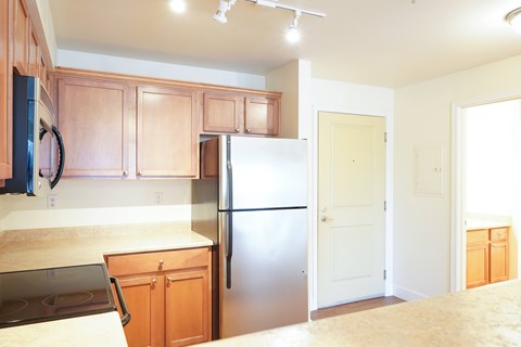 A kitchen with wooden cabinets and a stainless steel refrigerator.