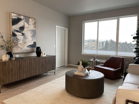 A living room with a brown couch, a brown coffee table, and a large painting on the wall.