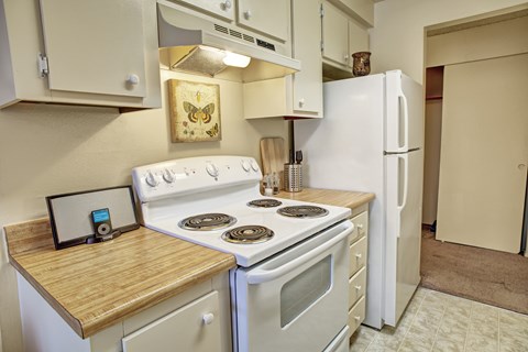 A kitchen with a white stove and a white refrigerator.