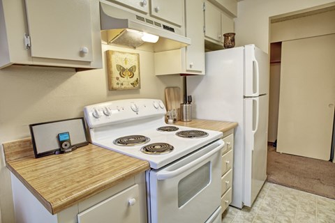 A kitchen with a white stove and a white refrigerator.