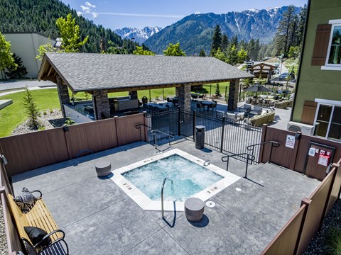 A hot tub sits in the middle of a patio with a mountain view.