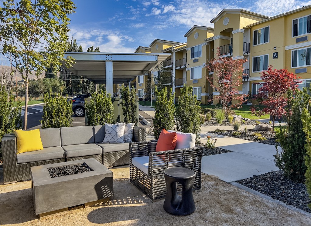 a patio with couches and a coffee table in front of an apartment building