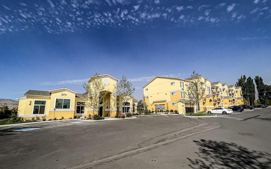 a row of apartment buildings with a parking lot in front of them