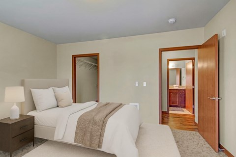 A bedroom with a bed, nightstand, and a mirror.