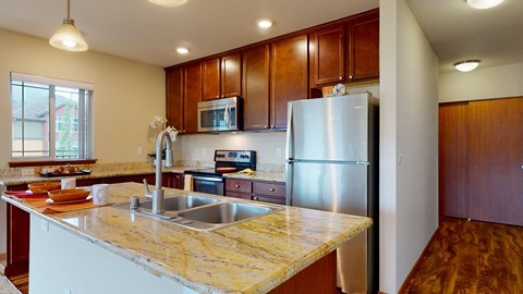 A kitchen with a marble counter top and stainless steel appliances.