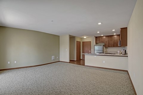 A spacious living room with a kitchen area in the background.