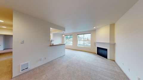 A large, empty room with a fireplace and a window.