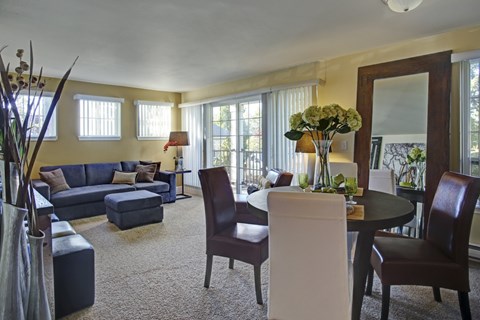 A living room with a blue couch and a round table with chairs.