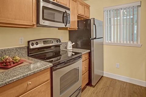 A black refrigerator is in a kitchen with wooden cabinets.