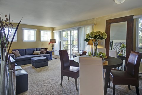 A living room with a blue couch and a round table with chairs.