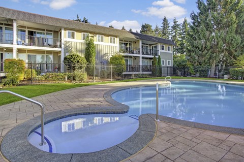 A swimming pool in front of a building with a fence around it.