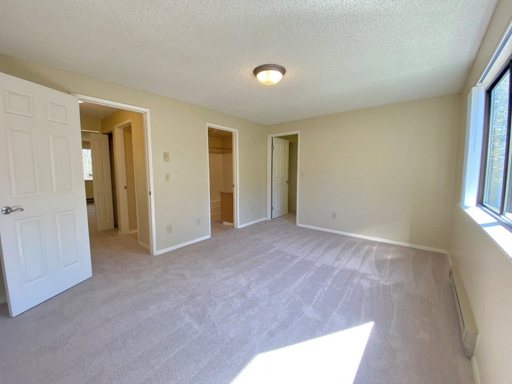 an empty living room with a white carpet and a white door and window