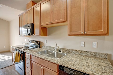 A kitchen with wooden cabinets and granite countertops.
