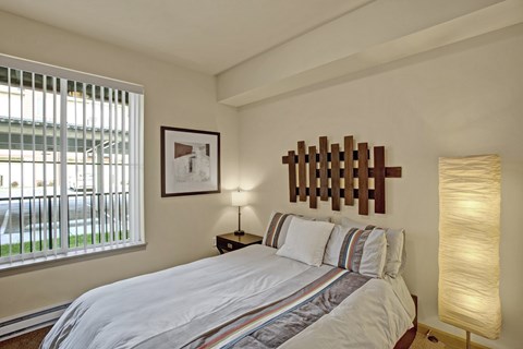 A bedroom with a bed, a lamp, and a picture on the wall.