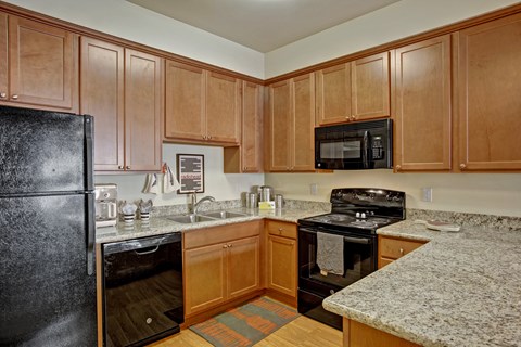 A kitchen with wooden cabinets and granite countertops.