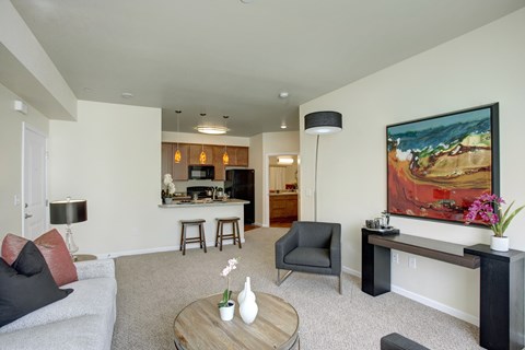 A living room with a grey couch, a coffee table, and a painting on the wall.