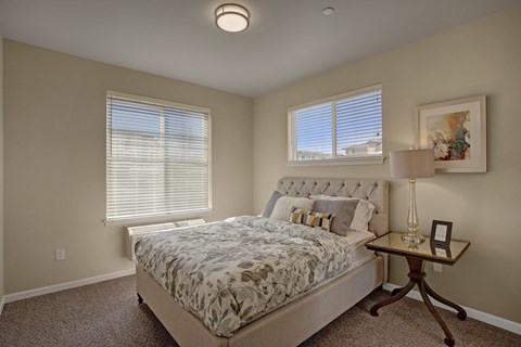 A bedroom with a large bed and a small table with a lamp.