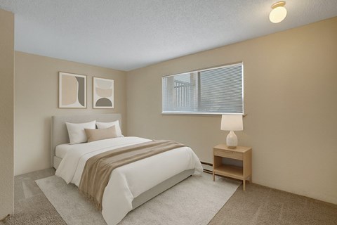 A cozy bedroom here at Soundview with soft carpet, bright window, and staged bed with neutral bedding creating a comfortable and inviting retreat.