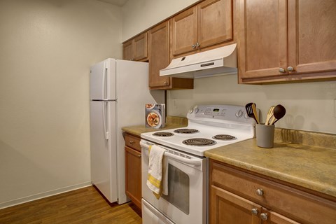 A kitchen with a white stove and wooden cabinets.