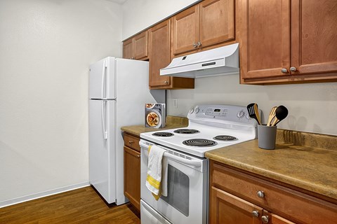 A white refrigerator sits next to a stove in a kitchen.