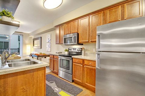 A kitchen with wooden cabinets and a stainless steel refrigerator.