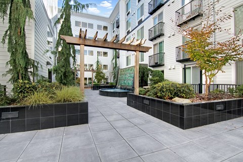 A courtyard with a wooden arch and a black tile border.