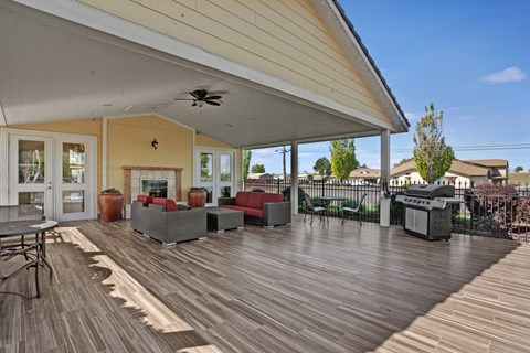 A wooden deck with a table and chairs is surrounded by a white wall.