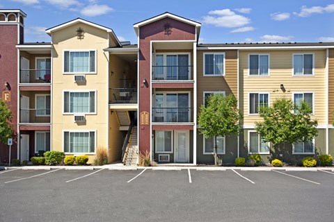 Apartment building with a parking lot in front.