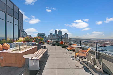 A rooftop patio with chairs and a view of the city.