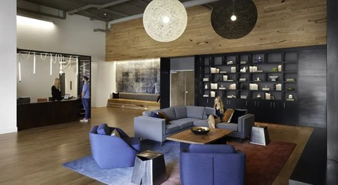 A woman is sitting on a blue couch in a modern living room.