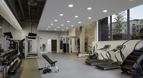 A modern fitness center here at Uptown at Kirkland Urban with treadmills, strength machines, and free weights, featuring bright lighting, expansive windows, and a clean, motivating space for energizing daily workouts.