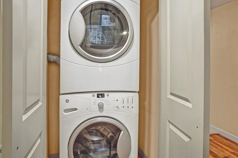 A laundry area here at Vermont featuring a stacked washer and dryer tucked behind double doors, offering a convenient, compact, and practical in-home laundry space.