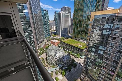 A view from a high-rise building looking down at a large, spherical sculpture in the middle of a park.
