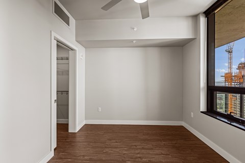 A room with a ceiling fan and a window overlooking a construction site.