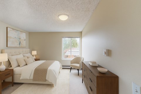 A bright bedroom here at Watercrest with soft carpet, neutral walls, and a large window, featuring a comfortable bed with light bedding, matching bedside tables with lamps, and a wooden dresser, creating a warm and relaxing atmosphere.