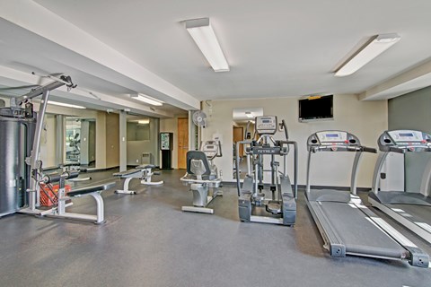 A well-equipped fitness center here at Watercrest with cardio machines, strength equipment, and free weights, featuring mirrored walls and bright lighting, creating a convenient and motivating space for resident workouts.