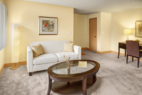 A living room with a white couch, a coffee table, and a painting on the wall.