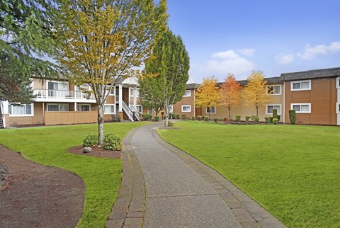 A residential area with apartment buildings and a sidewalk.