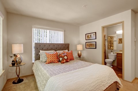 A bedroom with a large bed and a window with blinds.