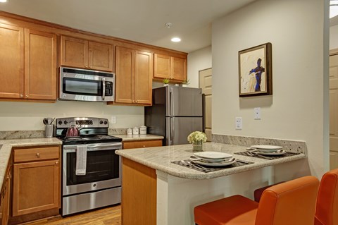 A kitchen with a stove, refrigerator, and orange chairs.