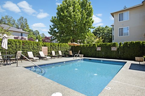 A small pool with a slide and lounge chairs.