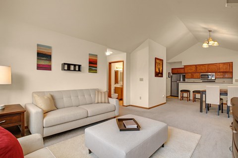 A living room with a white couch and a grey ottoman.
