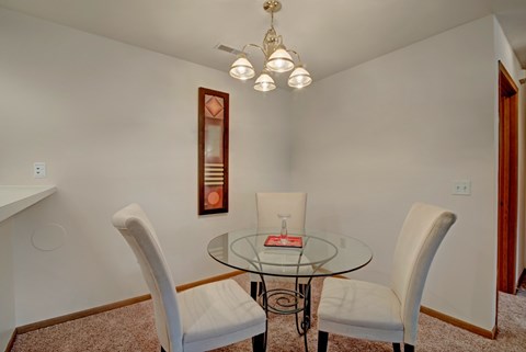 A glass table with a red book on it and two chairs.