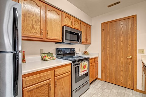 A kitchen with wooden cabinets and a stainless steel refrigerator.