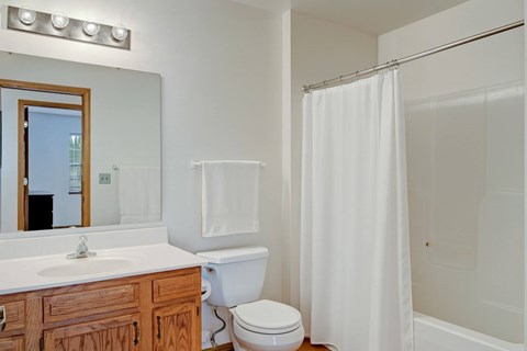 A white bathroom with a toilet, sink, and shower.