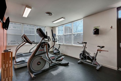 A bright fitness center here at Latitude featuring large corner windows, modern cardio equipment, and a clean, open layout, creating an energizing and welcoming workout space.