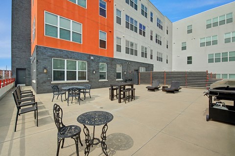 A spacious outdoor patio here at Latitude featuring stylish seating areas, café tables, lounge chairs, and grilling space, creating a bright and inviting setting for relaxing and socializing.